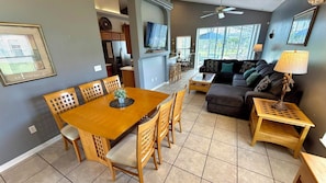 A dining area with a wooden table and chairs, a living room with a sofa and a lamp, and a kitchen with cabinets and a refrigerator. - Spacious 4-Bedroom Villa with Private Pool in Glenbrook – Your Ideal Orlando Getaway (Clermont)