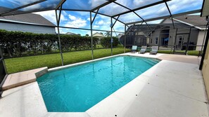 Una piscina con zona cubierta, rodeada por una valla y un edificio al fondo.