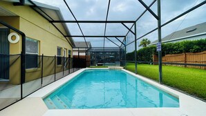 Una piscina rectangular con cerramiento de cristal, rodeada por una valla de metal.