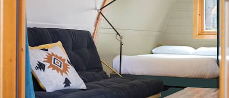 A cozy room with a dark-colored sofa, a bedside table, a lamp, and a bed with white bedding.