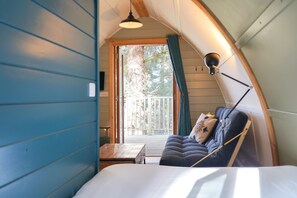 A cozy room with a bed, a table, and a view of the outdoors. - Deluxe Cosy Cabin With Wood Fired Hot Tub (Spalding)