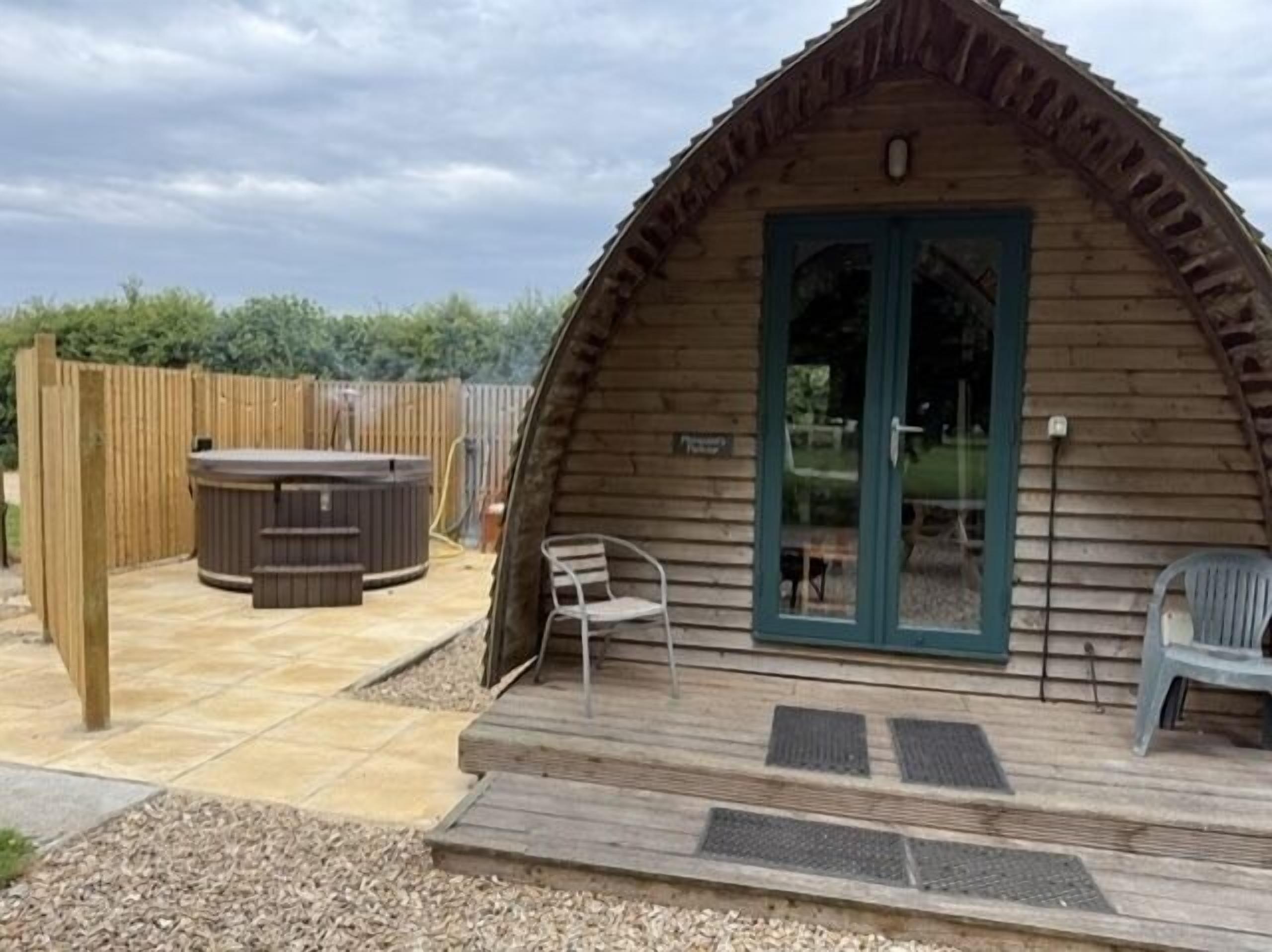 A wooden cabin with a porch, a hot tub, and a patio area.