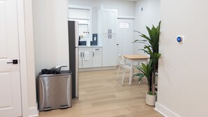 A modern kitchen with white cabinets, a stainless steel refrigerator, and a wooden dining table. - Modern 1BR in Central Philly Near Hospitals, Parks, WiFi + Housekeeping (Philadelphia)