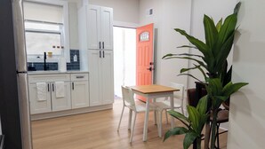 A modern kitchen with white cabinets, a wooden table, and a potted plant. - Modern 1BR in Central Philly Near Hospitals, Parks, WiFi + Housekeeping (Philadelphia)