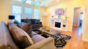 A living room with a sofa, coffee table, fireplace, and artwork on the wall. - Sunmist Farm House in a 35 acres grove (Temecula)
