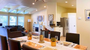 A dining area with a table set for four, a chandelier, and a kitchen in the background. - Sunmist Farm House in a 35 acres grove (Temecula)