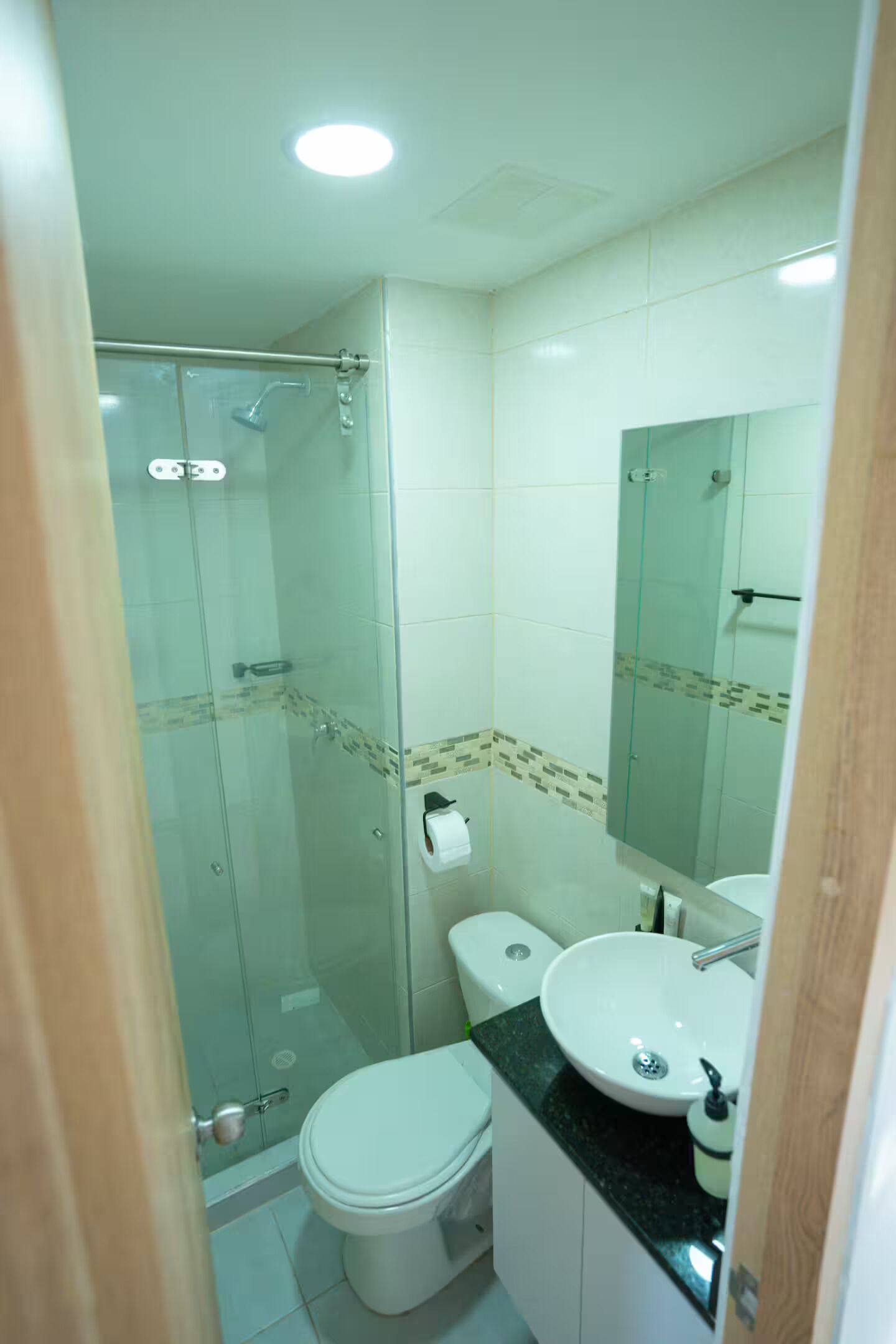 Une salle de bain avec une douche à parois de verre, des toilettes et un lavabo avec un miroir au-dessus.