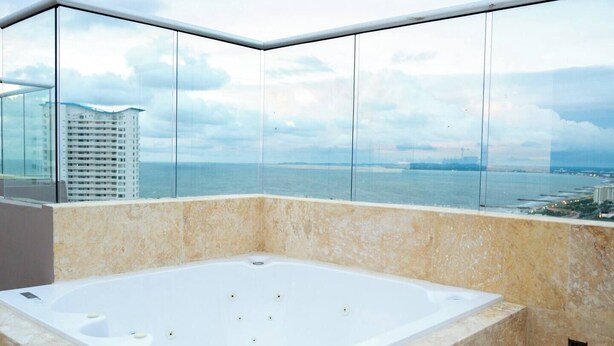 Ein modernes Badezimmer mit einer großen Badewanne und Meerblick durch große Fenster.
