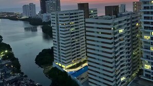 Ein Hochhaus mit mehreren Balkonen, einem Schwimmbad und einem Fluss im Vordergrund.