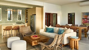 A modern living room with a sofa, chairs, a coffee table, and a dining area with a table and chairs.