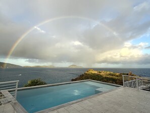 A swimming pool with a view of the ocean and a rainbow. - NEW Villa Arpeggio Luxury Oceanfront (Northside)