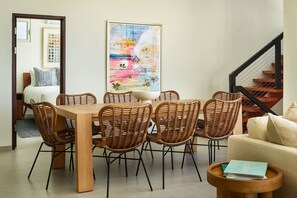 A dining area with a wooden table and wicker chairs, a sofa, and a staircase. - NEW Villa Arpeggio Luxury Oceanfront (Northside)