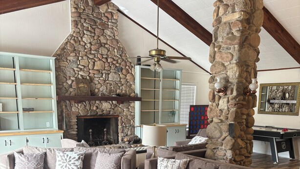 A cozy living room with a stone fireplace, a wooden coffee table, and a stone pillar. - Country Home, 4 Bed, 3.5 Bath, Pet Friendly (Warren)