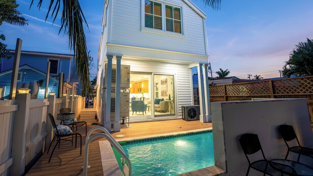 A two-story house with a swimming pool, a covered deck, and a patio area with chairs. - SOUTHERN CROSS: 3 BR, 3.5 BA home in Old Town Key West with Private Pool & AC! (Key West)