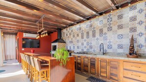 A modern kitchen with a wooden bar, a TV, and a patterned backsplash.