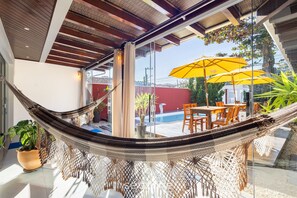 A hammock in a modern room with a glass wall, a pool, and outdoor furniture. - House With Pool and BBQ 190m From the sea Wpe0304 (Penha)
