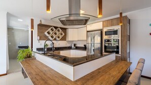 A modern kitchen with a central island, built-in appliances, and a unique geometric backsplash.