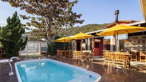 A pool area with wooden deck, yellow umbrellas, and outdoor seating.