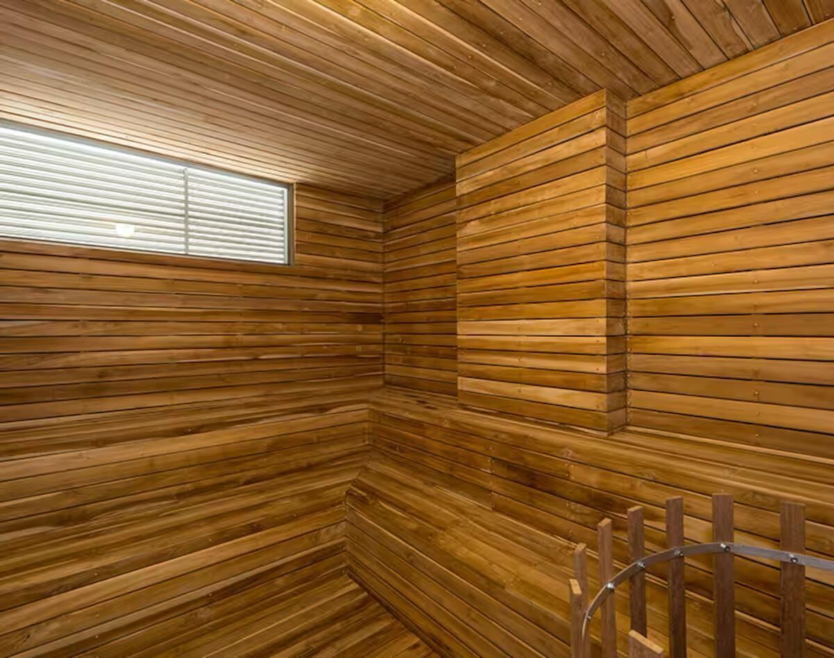 A room with wooden paneling, a window, and a metal railing.