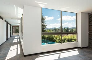 Ein Korridor mit großen Fenstern, Blick ins Grüne und einem Pool.