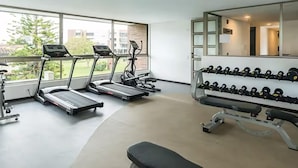 Ein Fitnessstudio mit Laufbändern, Kurzhanteln und einer Trainingsbank.