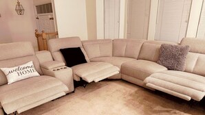 Ein modulares Sofa mit einem 'welcome home'-Kissen, ein kleiner Hocker und ein flauschiges Kissen.
