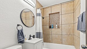 A bathroom with a bathtub, a sink, a mirror, and a shower curtain.