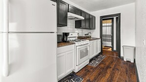 A kitchen with white cabinets, a stove, a microwave, and a refrigerator.