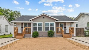 A two-story house with a front porch, a gravel driveway, and a wooden fence.