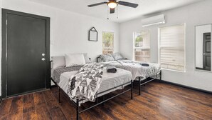 A bedroom with two beds, a ceiling fan, and a door.
