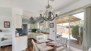 Una cocina moderna con armarios blancos, encimera de madera y una zona de comedor con mesa dispuesta para cuatro.
