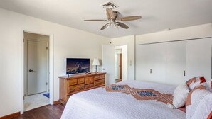 Un dormitorio con una cama, ventilador de techo, cómoda, armario y una puerta.