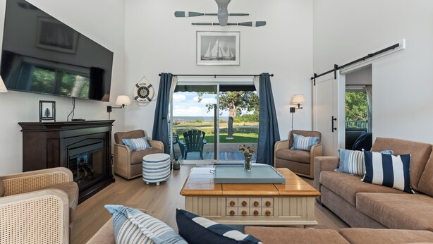 A spacious living room with a fireplace, comfortable seating, a large TV, and a view of the outdoors. - New Waterfront Luxury Cabin on Lake Winnipeg (Matlock)