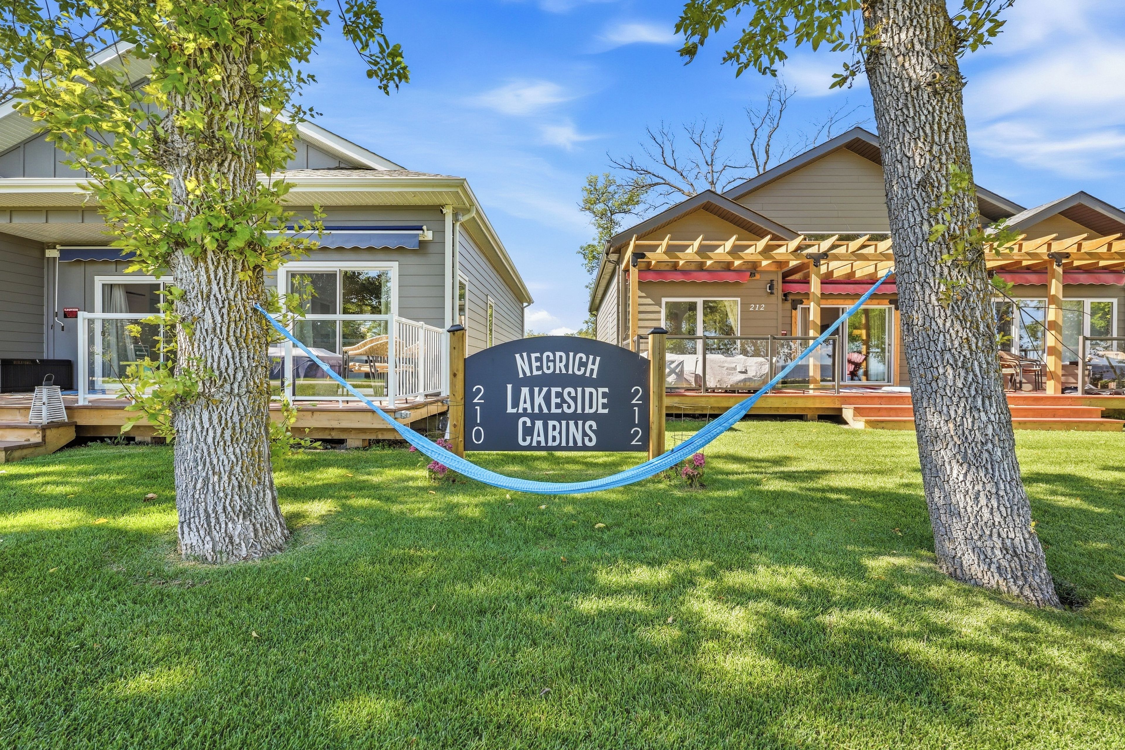A sign for Negrich Lakeside Cabins with a clear view of the cabins and surrounding trees.