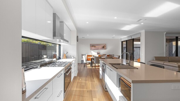 A modern kitchen with a central island, a dining area with a view, and a living space with a sofa. - The Turnstone Retreat (Cowes)