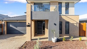 A modern two-story house with a garage, a balcony, and a well-maintained garden. - The Turnstone Retreat (Cowes)