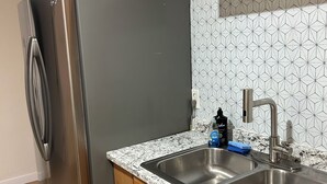 Una cocina con refrigerador de acero inoxidable, encimera de granito, armarios de madera y salpicadero con diseño geométrico.