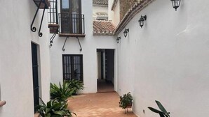 A narrow courtyard with terracotta tiles, potted plants, and white walls. - Mills 1 bedroom (Constantina)