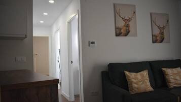 Un salon avec un canapé de couleur sombre et deux tableaux représentant des cerfs accrochés au mur.