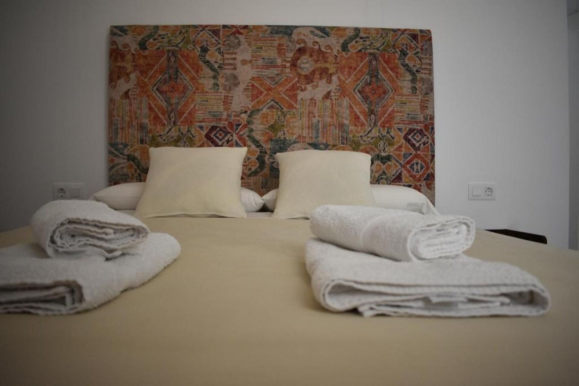 Een hotelkamer met een bed, twee kussens en twee opgerolde handdoeken.