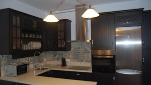 A modern kitchen with dark cabinetry, a stainless steel refrigerator, a microwave, and a sink. - Bodeguetas 1 bedroom (Constantina)