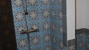 A shower with a handheld showerhead and a vertical rain showerhead, set against a patterned tile wall. - Bodeguetas 1 bedroom (Constantina)