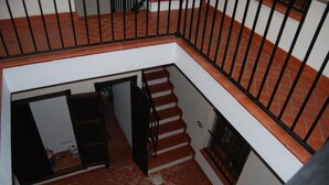 Una escalera con barandilla metálica, un tapete estampado y un cuenco de metal en el suelo.