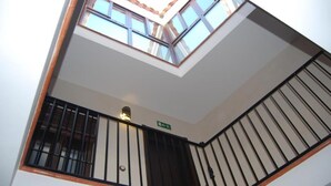 Vista de un balcón con tragaluz, barandilla de metal y letrero de salida verde.