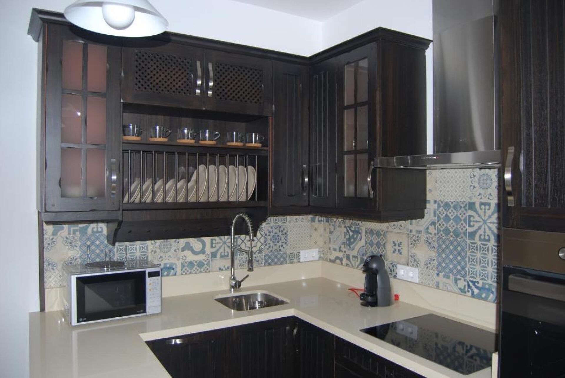 Una cocina con armarios de madera oscura, microondas, fregadero y cafetera.