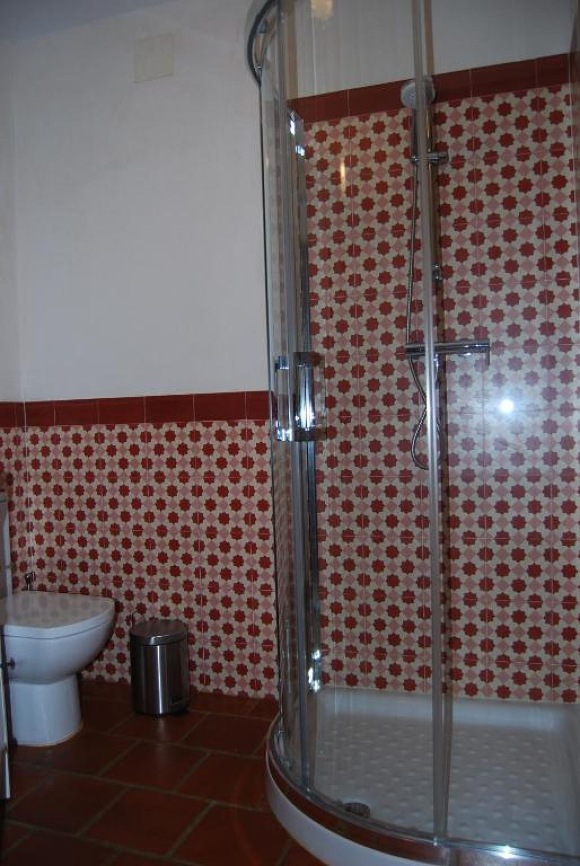 Un baño con ducha, inodoro y cubo de basura.
