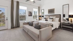 A modern bedroom with a large bed, a sofa, a ceiling fan, and a view of the outdoors. - Houston Family Retreat | Sleeps 10 | Near NRG (Houston)