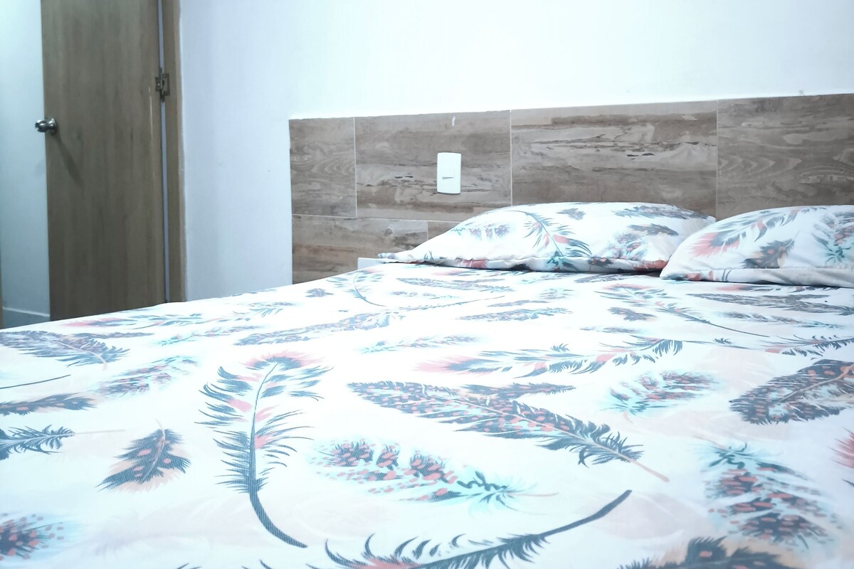 Ein Schlafzimmer mit Holztür, einem Bett mit blumigem Überwurf und einem schlichten Kopfteil.