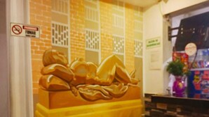 A restaurant interior with a brick wall, a large bread sculpture, and a table with chairs. - Hotel Casa Girardot (Medellin)