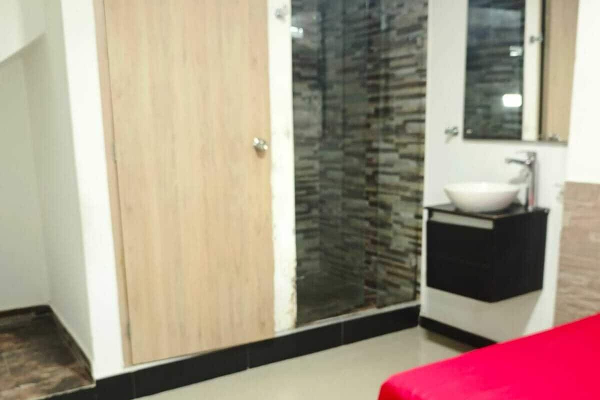 Ein Schlafzimmer mit Bett, Kleiderschrank, Badezimmer mit Waschbecken und Spiegel.